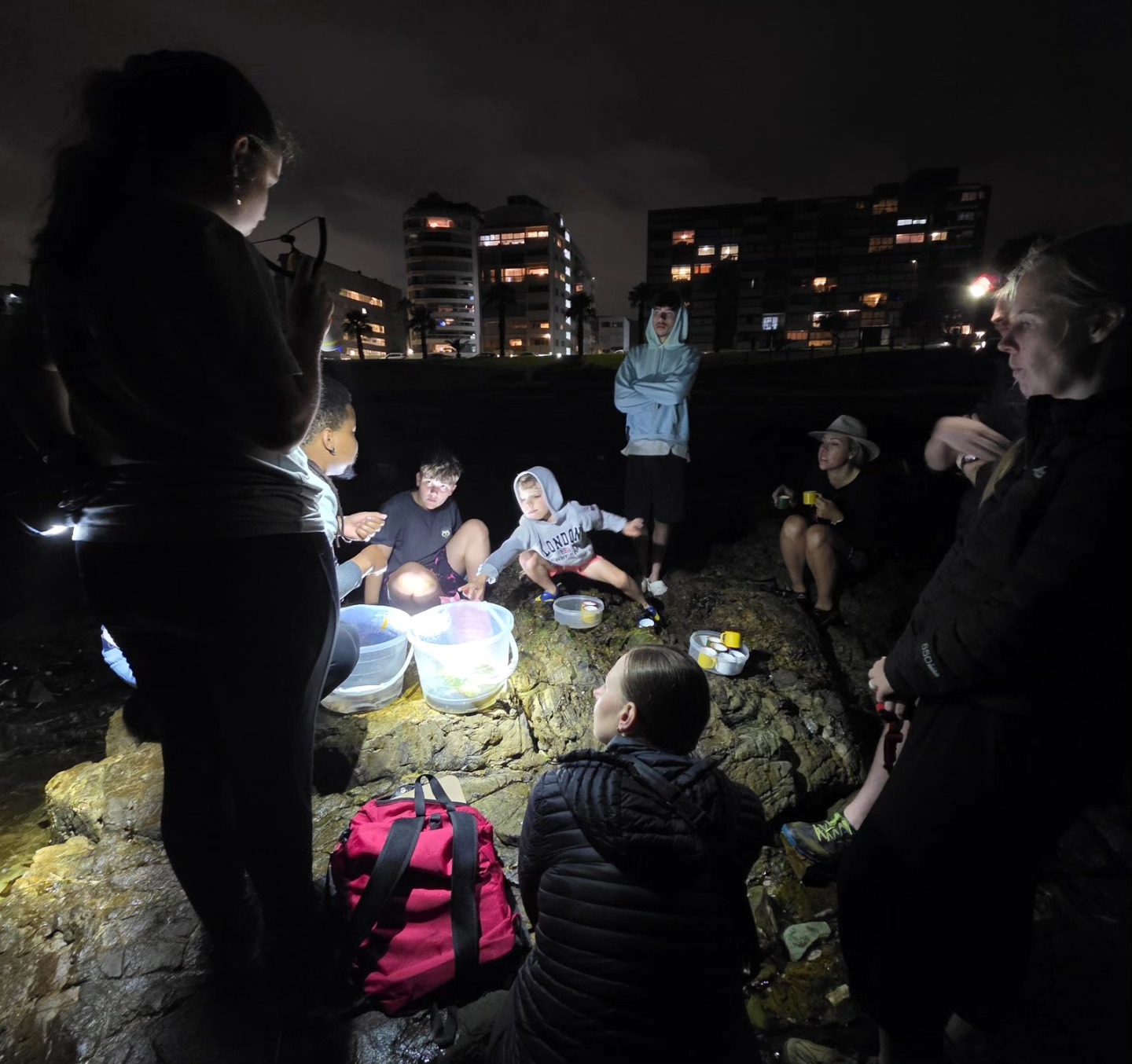 Guests gathered on the rocks at night around lit specimen trays